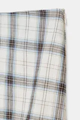 Falda midi de tiro bajo con estampado de cuadros en tonos beige, azul y negro. Presenta un diseño asimétrico en el bajo y cierre lateral con cremallera oculta.