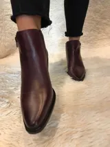 Botín negro de cuero con punta fina y taco de bloque. Tiene cierre lateral y caña baja.