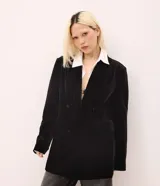 Blazer de terciopelo color negro con largo extendido, diseño cruzado con botones frontales, solapa clásica, bolsillos con tapa y mangas largas.