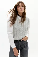 Chaleco de punto color gris melange, con cuello redondo, sisa amplia y largo a la cadera. Presenta un diseño de ochos tradicionales.