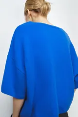 Jersey de punto liso color azul eléctrico, con cuello redondo y mangas anchas de corte caído.