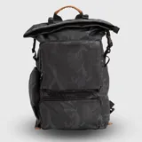 Mochila urbana de diseño funcional en color mostaza, confeccionada en material repelente al agua. Cuenta con cierre superior enrollable con hebillas ajustables, un compartimento frontal grande con cierre, un bolsillo inferior adicional con el logo de la marca, compartimentos internos organizadores, funda acolchada para laptop y bolsillos laterales para botellas.