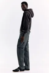 Pantalón cargo gris oscuro de nylon con corte estándar, cintura elástica con cordón ajustable, bolsillos con cierre en los laterales y bolsillos de parche con solapa en las piernas.