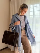 Saco oversize de tejido de punto color lavanda, con capucha, mangas anchas y flecos en el ruedo.