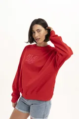 Buzo de algodón rojo con cuello redondo y mangas largas. Estampado frontal con el texto 'Pulau Dept. Since 2023' en color rosa.