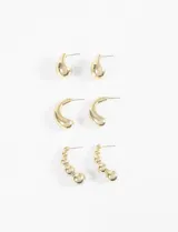 Set de tres pares de aros dorados: un par de aros tipo argolla gruesa, un par de aros con forma de gota y un par de aros colgantes con esferas de diferentes tamaños.