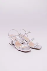 Sandalias de tacón cuadrado bajo, color plateado, con diseño de tiras tubulares acolchadas y cierre de pulsera con hebilla en el tobillo.