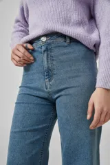 Pantalón de jean negro, de corte ancho y tiro alto, con ruedo deshilachado.