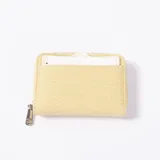 Monedero compacto de color amarillo con textura trenzada, cierre perimetral de cremallera con tirador metálico y un compartimento exterior portatarjetas.