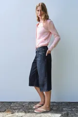 Chaqueta de punto color rosado con cuello polo, manga larga y cierre frontal con botones.