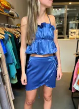 Minifalda cruzada azul de satén con lazo lateral.