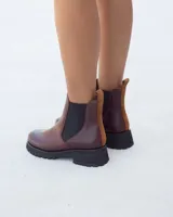 Botas tipo Chelsea de cuero color marrón, con paneles elásticos laterales en color negro y suela de goma dentada en color negro. Presenta un detalle de tirador en la parte trasera en gamuza color tostado.