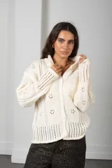 Cárdigan de punto color blanco con diseño calado de motivos florales, cuello alto, cierre frontal con botones y mangas largas con puños acanalados.