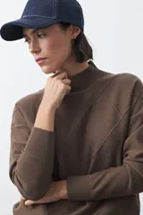 Polera de tejido de punto color gris oscuro, con cuello alto y diseño de rombos en relieve en el frente. Presenta un calce relajado con terminaciones en rib en cuello, puños y ruedo.