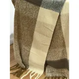 Bufanda rectangular de tejido grueso con diseño de cuadros en tonos azul, naranja, gris y beige, terminada con flecos en los extremos.