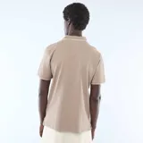 Remera polo de piqué de algodón color beige, con cuello y puños con ribete blanco, cierre frontal con botones y pequeño logo bordado en el pecho.