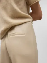 Pantalón tobillero color beige, de corte flare y tiro alto.