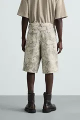 Bermuda relaxed fit de algodón, color beige con estampado abstracto en tonos grises. Cuenta con cinco bolsillos y cierre frontal de cremallera y botón.