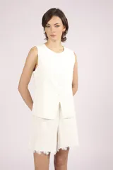 Chaleco blanco sin mangas, con cuello redondo y cierre frontal de botones. El chaleco tiene un corte recto y ligeramente holgado.