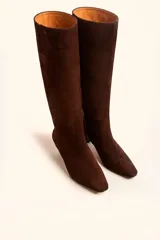 Bota de caña alta confeccionada en gamuza color marrón, con diseño minimalista, punta fina y taco kitten heel de 6 cm.