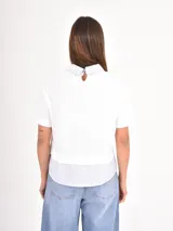 Remera de manga corta color blanco con cuello camisero y detalle de bajo en tela rayada azul y blanca, simulando una camisa debajo.
