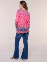 Remera evasé de manga tres cuartos y escote bote, confeccionada en rayón elastizado de color rosado con textura flameada y estampado floral en tonos fucsia y azul.