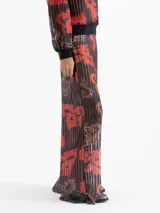 Pantalón Lexi de punto calado con estampado full print en tonos rojos, negros y marrones. Tiene cintura elastizada y bota amplia.