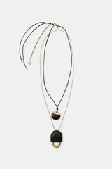 Pack de dos collares. Uno con cordón negro y colgante ovalado de resina marrón y metal dorado. El otro con cordón metálico dorado y colgante de pieza metálica con aplicación de piel verde. Ambos con cierre de bola ajustable.