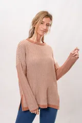 Sweater de punto color salmón con rayas verticales en relieve. Tiene cuello redondo y corte holgado.