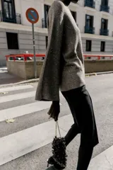 Jersey de punto color marrón oscuro con lentejuelas plateadas, cuello barco y manga larga acampanada.