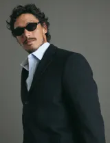 Sobretodo 3/4 de paño, color gris oscuro, con cuello solapa, cierre frontal de botones, manga larga y bolsillos laterales de ribete.