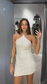 Vestido corto de encaje blanco con diseño de red, escote halter y corte ajustado al cuerpo.