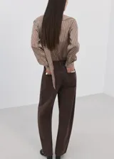 Blusa de rayas verticales marrones y blancas, con cuello alto y bufanda integrada para anudar al cuello, cierre frontal con botones y manga larga.