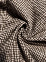 Chaqueta corta de estilo trench con estampado de cuadros pequeños, cuello alto, cierre frontal de doble botonadura y mangas con trabillas ajustables en los puños.