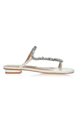 Sandalia flat color blanco con tira delantera adornada con piedras brillantes.