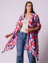 Kimono tejido con estampado floral en tonos rosa, rojo, azul y negro. Tiene terminación de ruedo con borlas negras.
