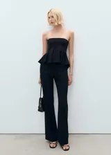 Top negro de escote palabra de honor con diseño peplum en la cintura. Confeccionado en tejido elástico con caída estructurada.