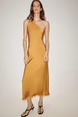 Vestido midi de satén color mostaza con escote asimétrico de un solo hombro y corte evasé. Presenta pliegues en el hombro y cierre lateral con cremallera oculta.