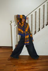 Bufanda tejida a máquina con diseño de rombos en tonos marrón, azul, verde y amarillo. Terminación con volados.