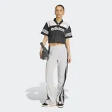 Pantalón deportivo Adidas Adibreak de color gris, con franjas negras laterales y las clásicas tres tiras blancas. Cuenta con botones a presión en los laterales, cintura elástica y diseño holgado.