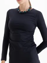 Top de lycra color violeta, con cuello redondo, mangas largas y detalle de frunces laterales en la cintura que aportan movimiento a la prenda.