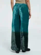 Pantalón palazzo de terciopelo verde esmeralda con efecto degradado a negro en la parte inferior.