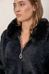 Campera de punto texturizado color beige, con cierre frontal completo y cuello de piel sintética al tono. Presenta mangas largas con puños ajustados y diseño holgado.