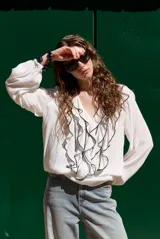 Blusa rosada de manga larga con escote en V, volados frontales con ribete negro contrastante y puños elásticos.