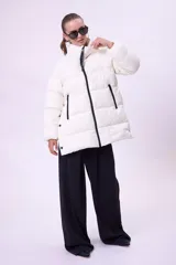 Campera puffer de corte oversize y largo medio, color blanco, con cuello alto, cierre frontal y aberturas laterales con botones a presión.