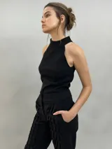 Pantalón tipo babucha confeccionado en lana de oveja, color visón. Presenta un diseño de tiro alto con textura vertical plisada a lo largo de las piernas, cintura con cierre de doble broche y puños elásticos en los tobillos.