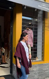 Ruana de lana Merino en color bordó, tejida en telar con diseño de hebras gruesas e irregulares y flecos en los extremos.