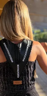 Minivestido negro con lentejuelas y flecos en el ruedo. Presenta un panel de tul transparente en el escote y cuello de cuero.