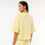 Camiseta de manga 3/4 en felpa color amarillo pálido, con cuello redondo y diseño holgado.