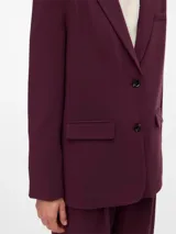 Blazer de corte oversize confeccionado en tejido plano color bordó, con cuello smoking, cierre frontal con botones y bolsillos delanteros con solapa.